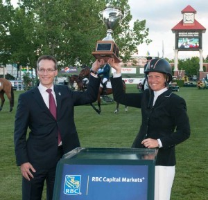 Beezie Madden and Derek Neldner, Managing Director, Global Investment Banking, RBC Capital Markets, lift the winning trophy. Photo © Spruce Meadows Media Services. 