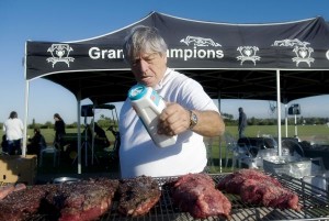 Cilantro's Gourmet Deli owner Herman Moreira puts the finishing spices on an assortment of meat served at Grand Champions post-game asado. Photo by Scott Fisher