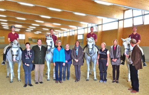 Suzie stands amongst Spanish Riding School riders and stallions in the indoor arena at Heldenberg with fellow students from Belgium, England, Norway, Germany and Austria.