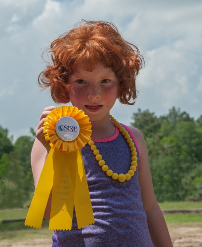 Emileigh Marsh shows off one of the ribbons won at the All SIRE Horse Show in May 2014.  Photo by Jaana Eleftheriou 