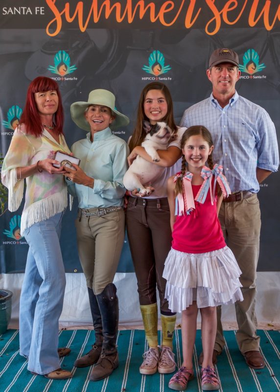 Henri is thrilled that her grandchildren love horses. From the left, Phyllis Gonzales, HIPICO leadership, Henri, granddaughters Blythe Bouza holding Eloise and Greer Bouza and their father Kevin Bouza at the HIPICO Santa Fe 2015 Summer Series. Photo by Adrian Wills
