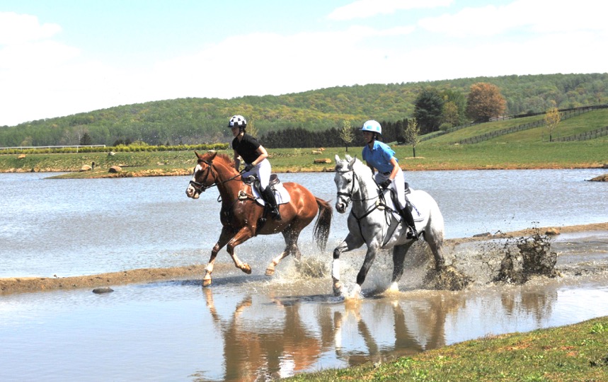 Connor Husain, on the chestnut, and Skyeler Voss, on the gray, gallop through the water at Morningside Farm. Photo by Lauren R. Giannini