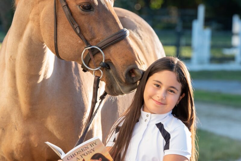 Gabi Caicedo with her pony, Q, and the book she wrote, “Chosen By a Pony.”